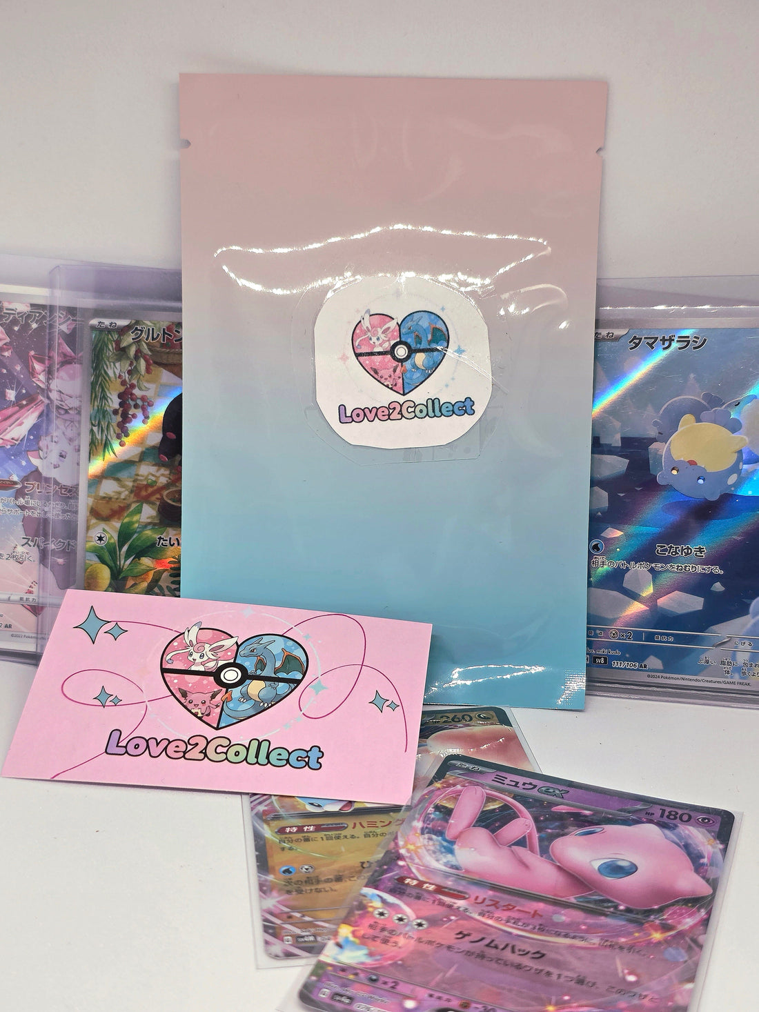 Pochette mystère Kawaii Love2Collect posée avec des cartes Pokémon