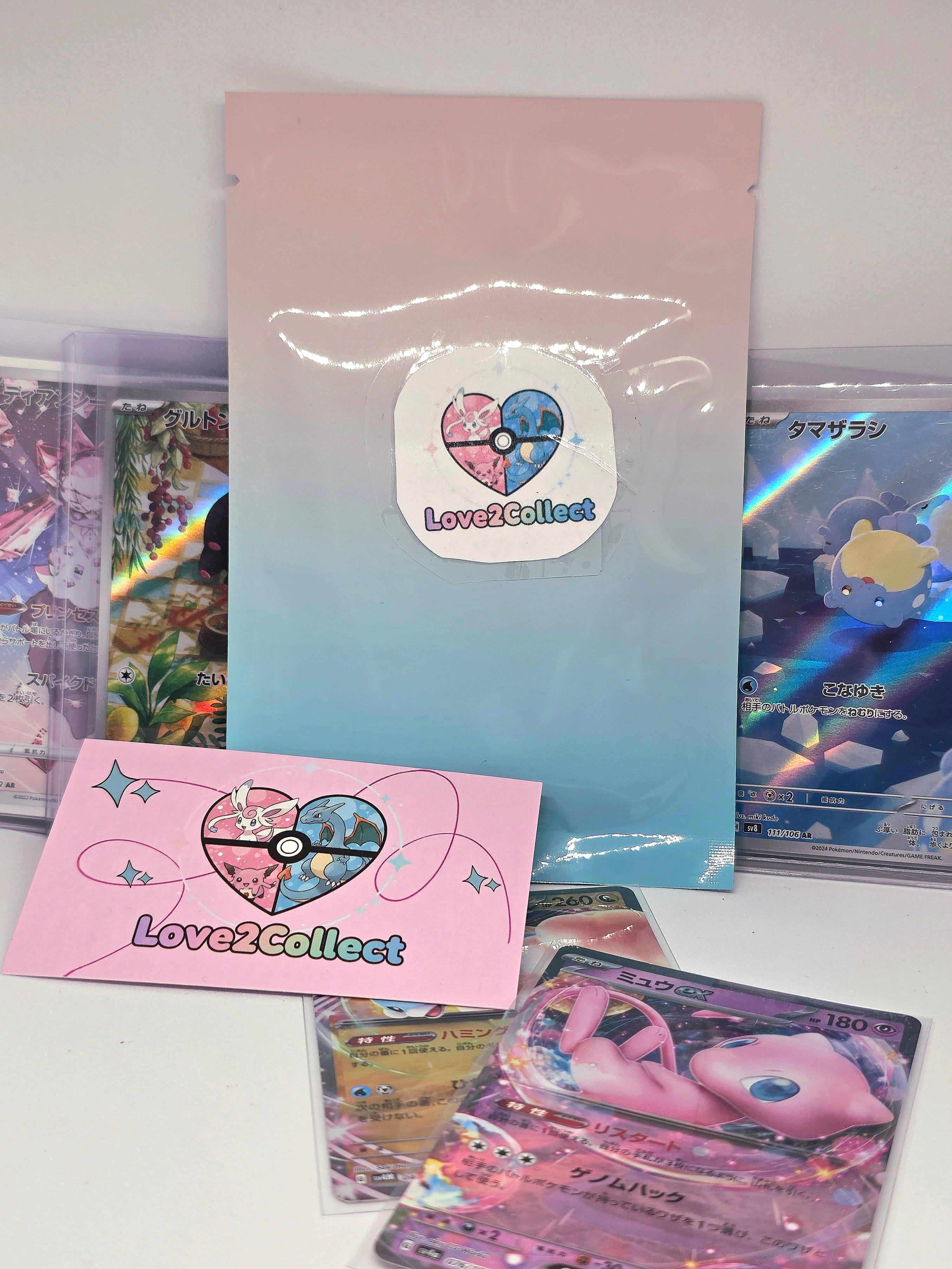 Pochette mystère Kawaii Love2Collect posée avec des cartes Pokémon