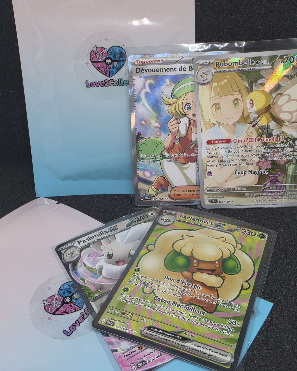 Pochette à thème kawaii de chez Love2Collect. On y vois la pochette en fond et plusieurs cartes Pokémon